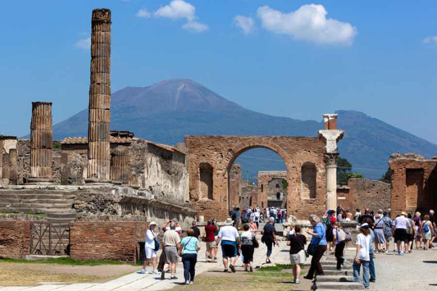 A group of tourists viisting pompeii during a sunny the day.